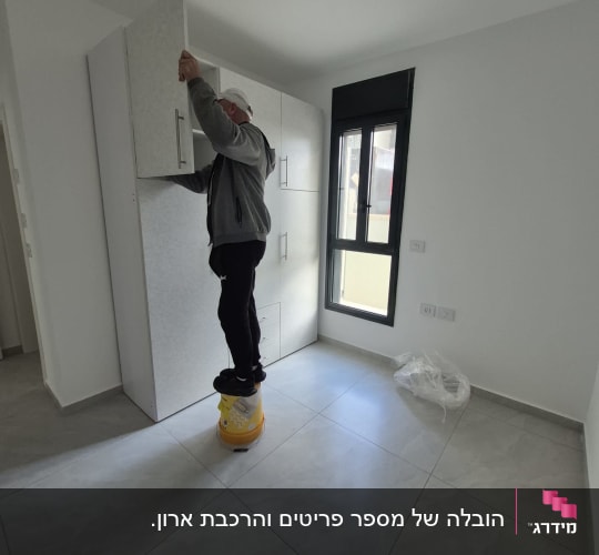 אדם מתקין ארון בחדר ריק עם חלון